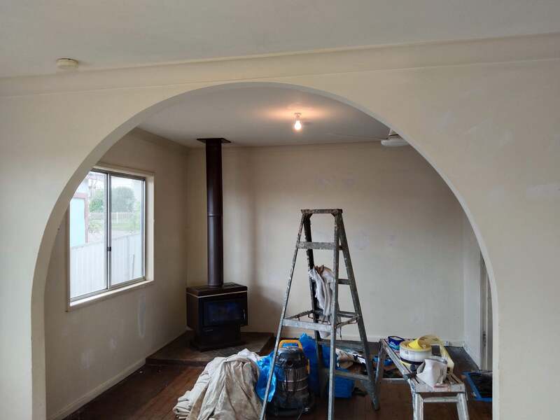 Livingroom of a home at Cessnock, unpainted, showing a painters ladder and tools. 